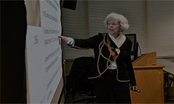 an elderly lady presenting something in a classroom environment