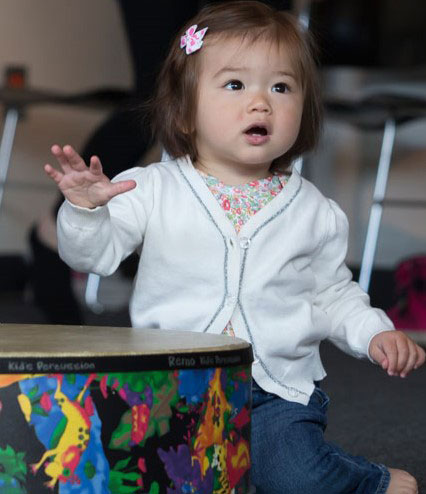 a small girl banging a drum
